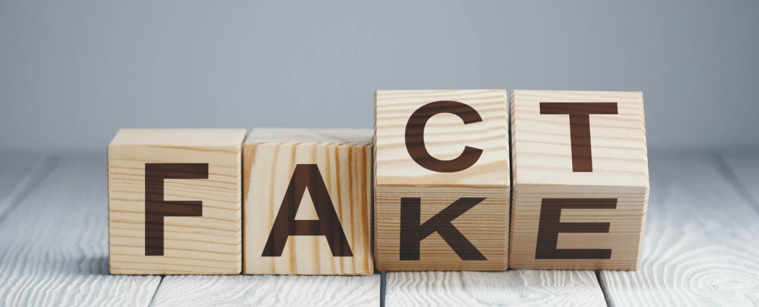 four wooden dice spelling out the words fake and fact
