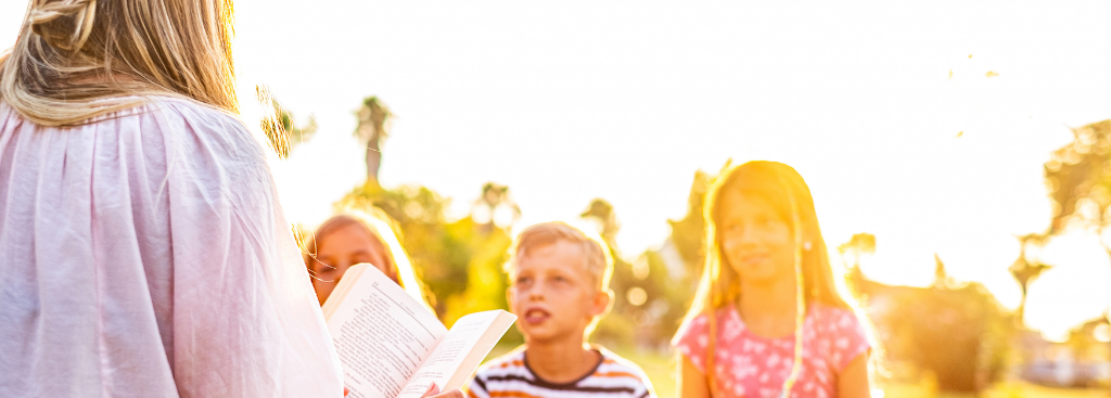 adult reading to children outside